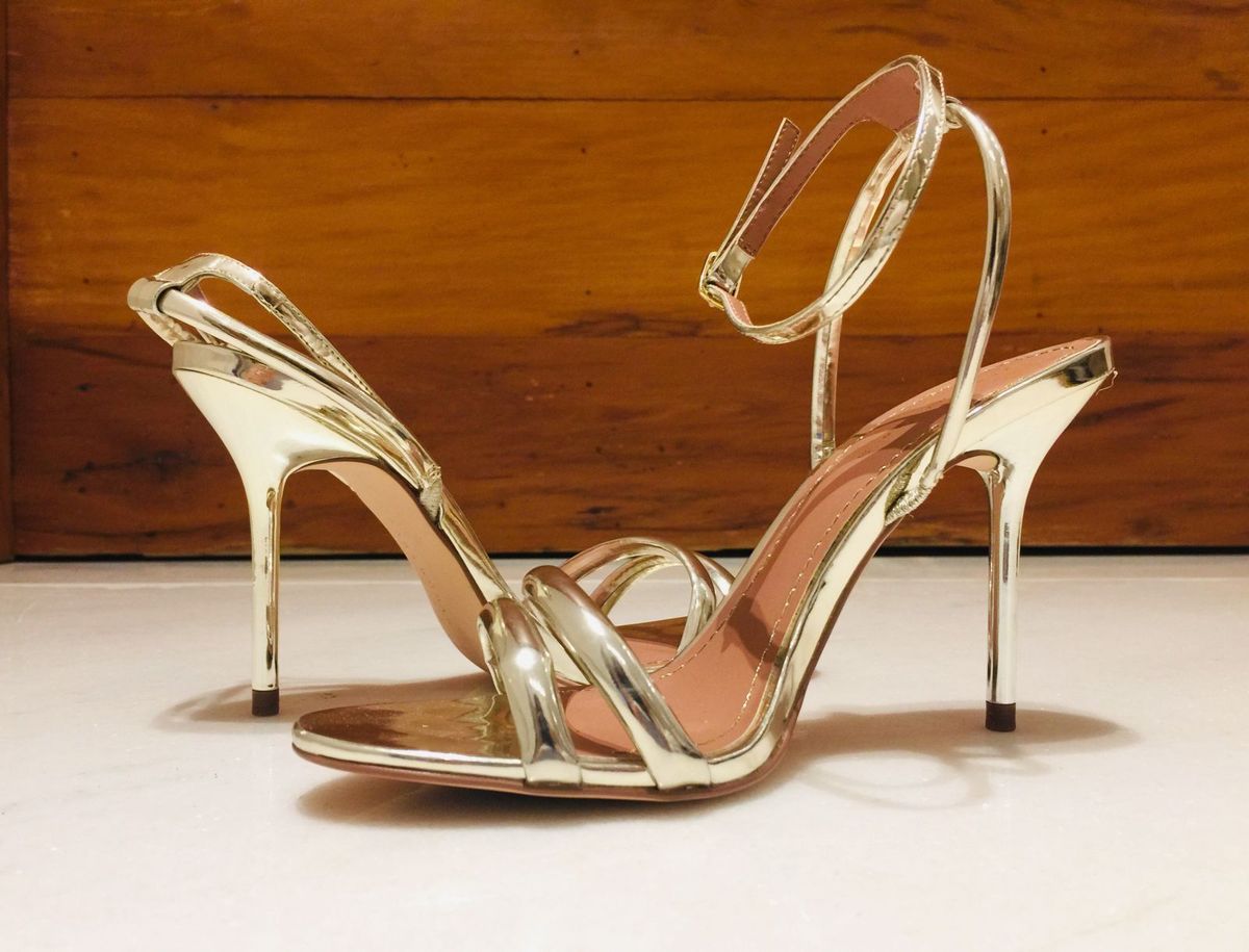 Sapatos dourados sobre fundo neutro, imagem do artigo Ansiedade na cidade